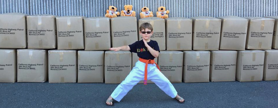 Bobby in front of stacked California Highway Patrol boxes with teddy bears